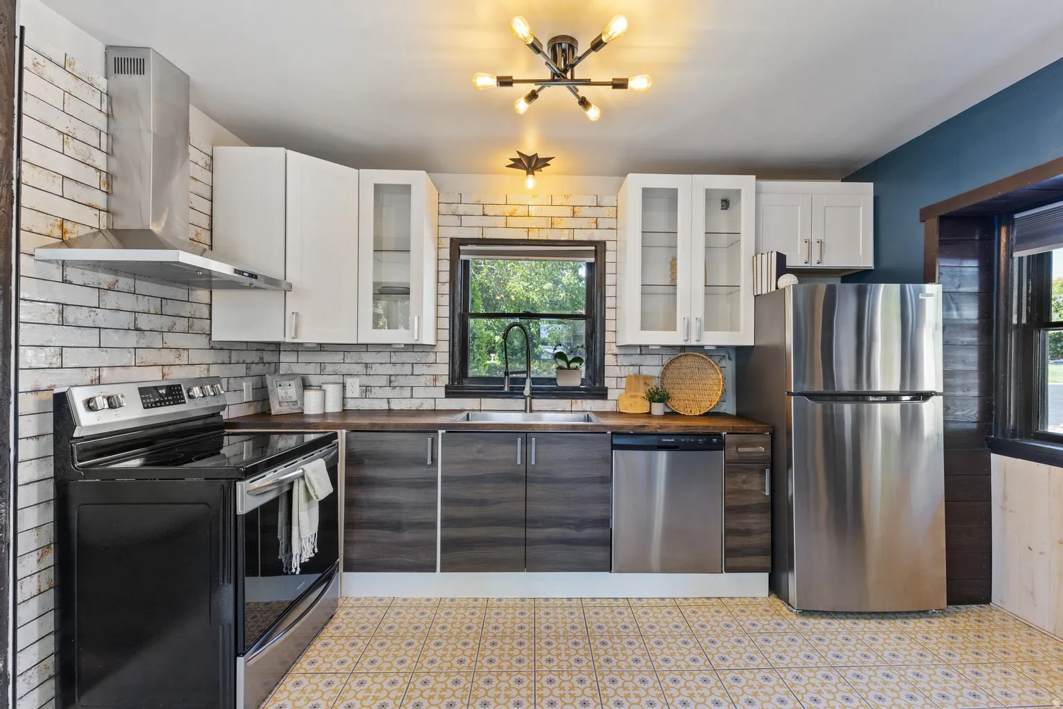 Kitchen featuring a stainless steel appliance suite, patterned floor tile, wood-finish countertops, and white brick-style tile backsplash