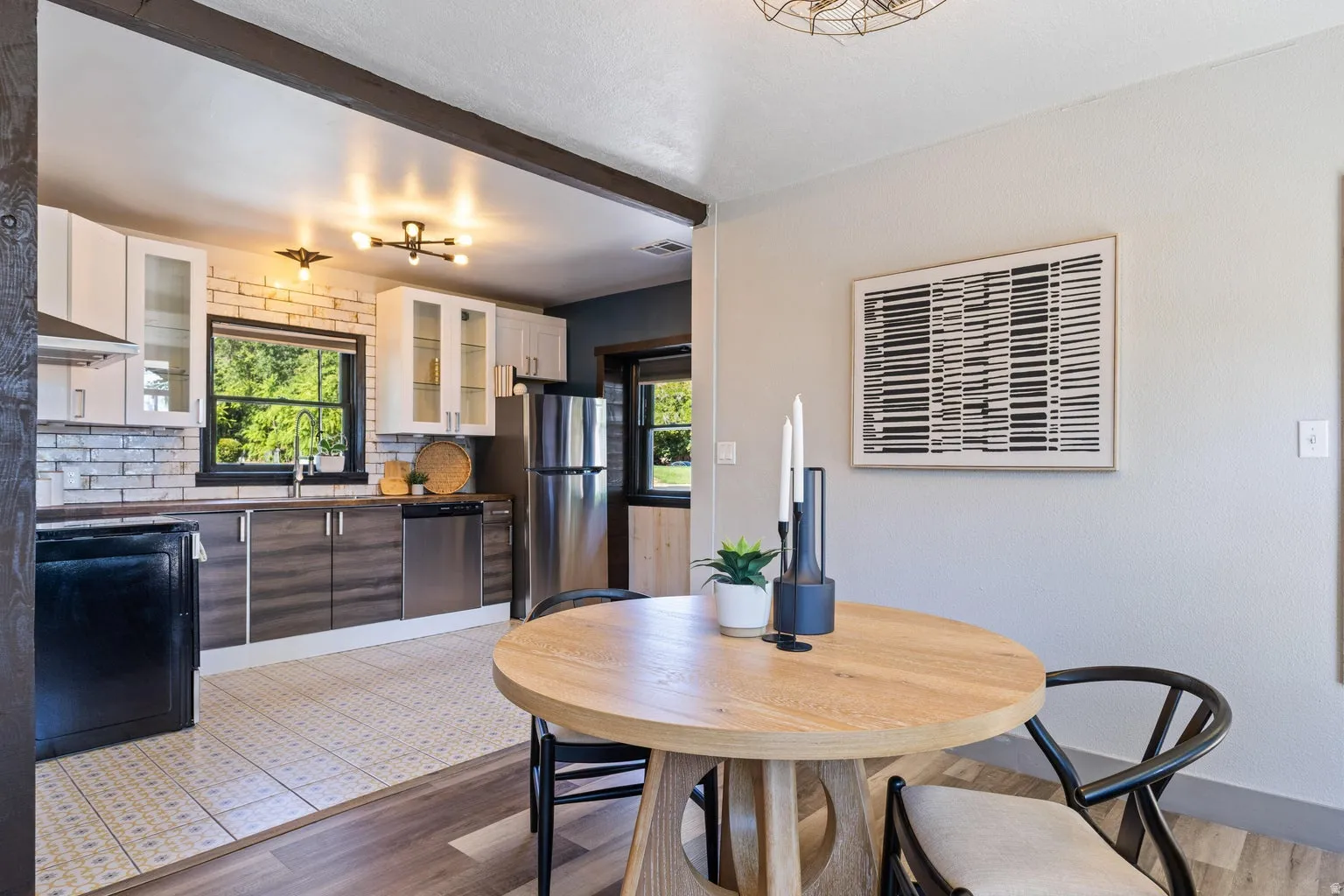 Kitchen featuring two-tone cabinetry, a tile backsplash, stainless steel appliances, and a window over the sink