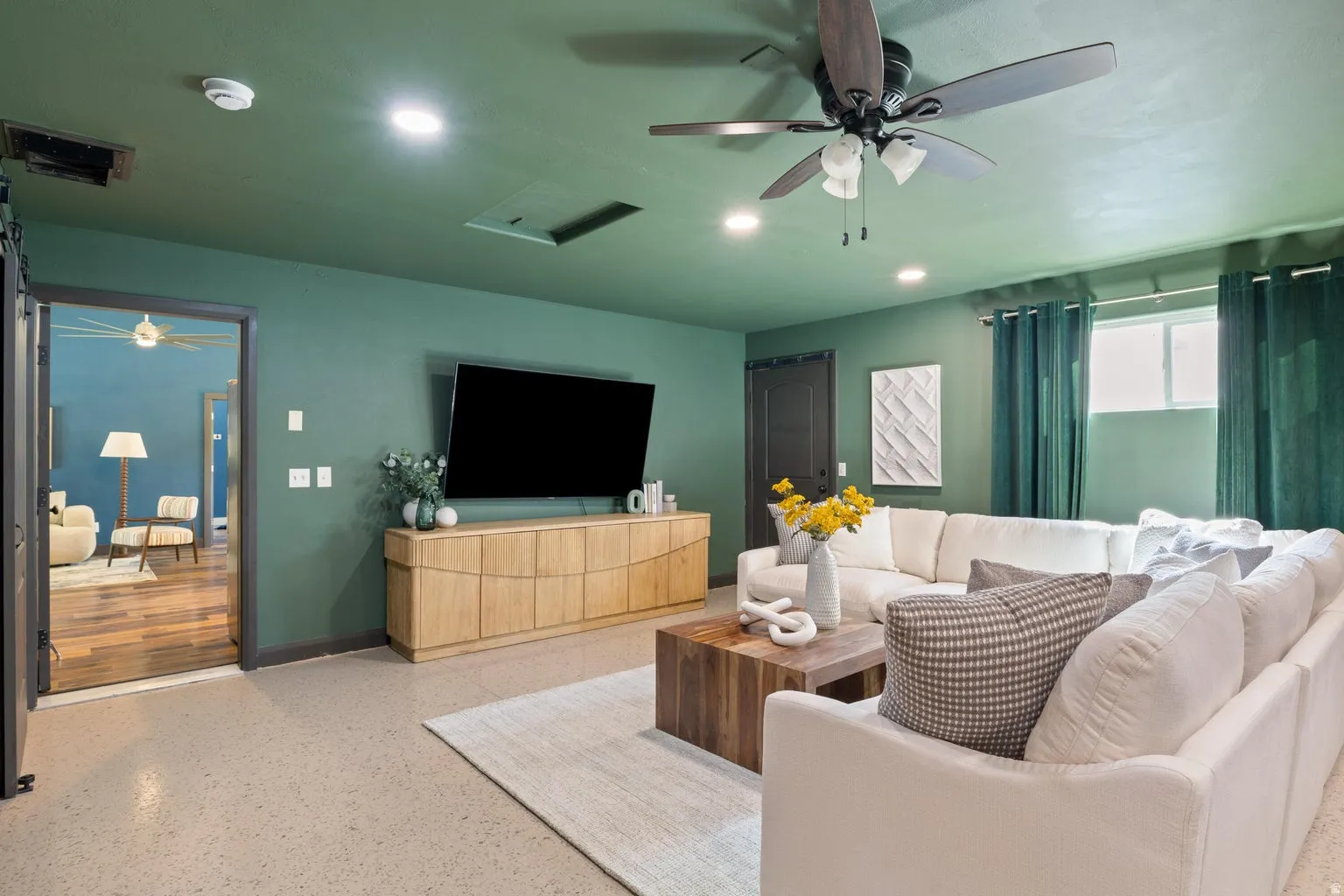 Recessed lighting, ceiling fan, natural light from window, wood-finish media console, and neutral flooring