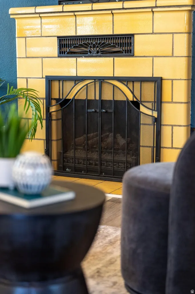 Fireplace featuring yellow tile surround, decorative metal grate, and black screen doors