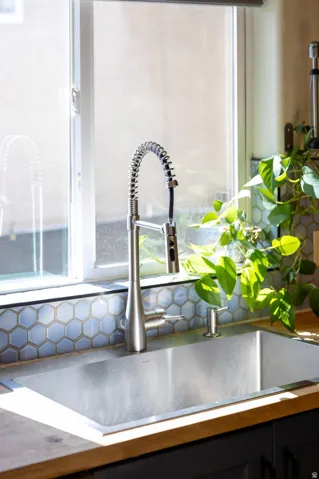 Stainless steel undermount sink with a brushed nickel pulldown faucet, set into wood-finish countertops, complemented by a hexagonal tile backsplash