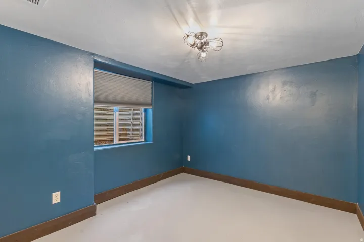 Neutral-toned flooring, vibrant blue walls, and a recessed window with an integrated shade