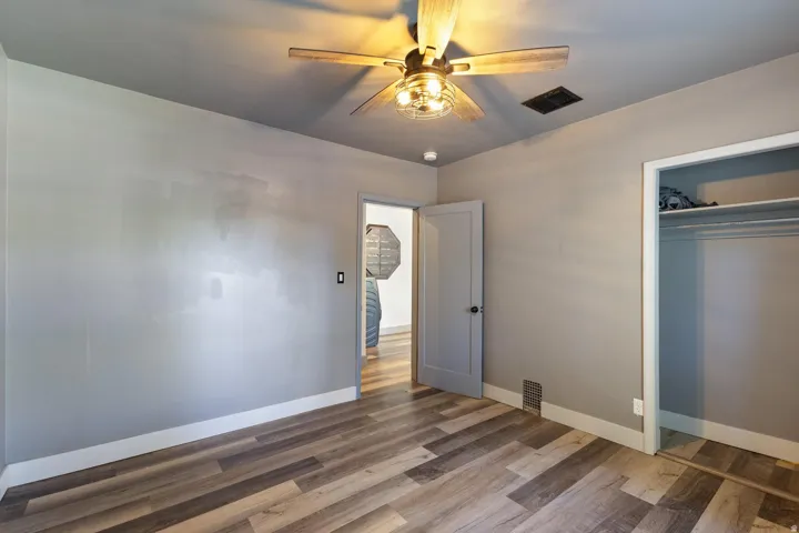 Wood-finish flooring, ceiling fan with integrated lighting, recessed ceiling light, and built-in closet with shelving