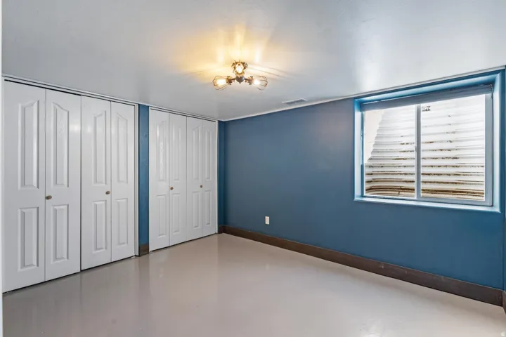 Recessed window with white blinds, dual bi-fold closet doors, and ceiling-mounted light fixture