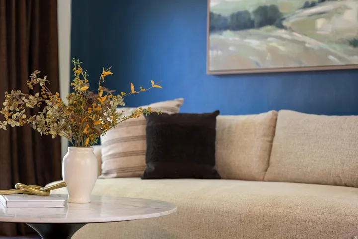 Textured fabric sofa, vibrant blue accent wall, framed artwork, and a round marble-top table