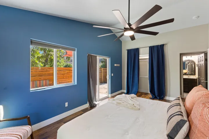 Vaulted ceiling with an integrated ceiling fan, wood-finish flooring, sliding glass door, and a built-in closet with shelving