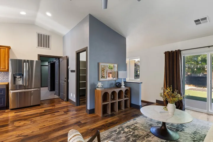 Vaulted ceilings, wood-finish flooring, stainless steel refrigerator, sliding glass door, and a built-in shelving unit