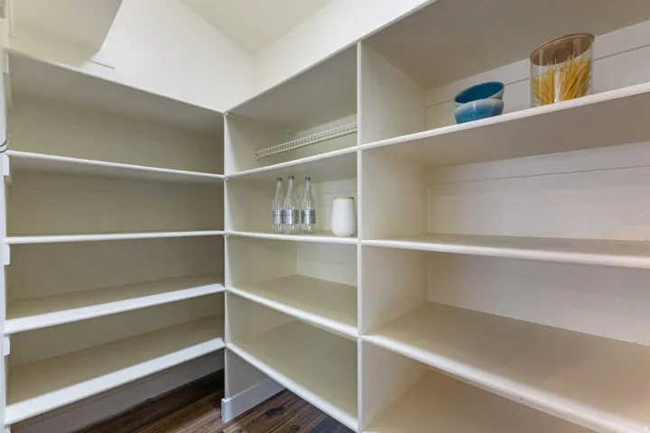 Integrated pantry shelving with ample storage, white finish, and wood-finish flooring