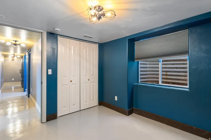 White bi-fold closet doors, a single window with a privacy blind, and a contemporary ceiling light fixture