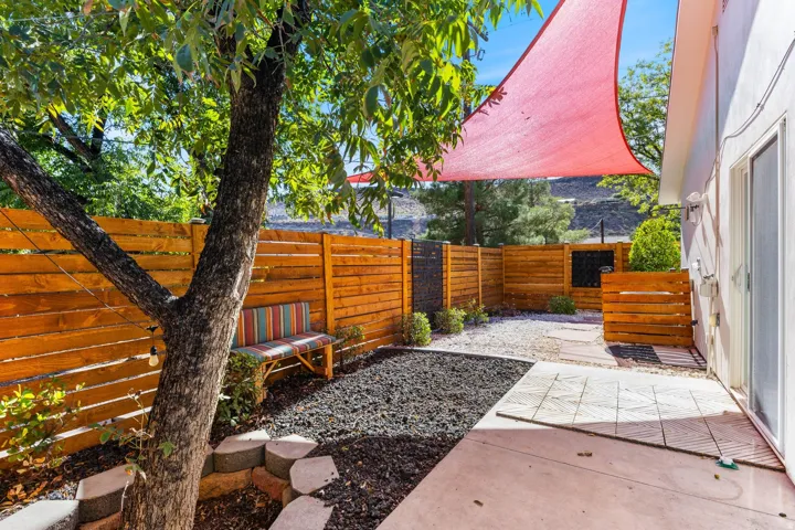 Private outdoor area featuring a wood-panel fence, concrete patio, and a red shade sail