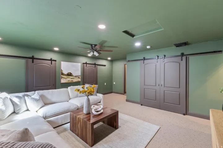 Recessed ceiling lights, ceiling fan, and multiple barn-style sliding doors on a wall with a consistent color palette