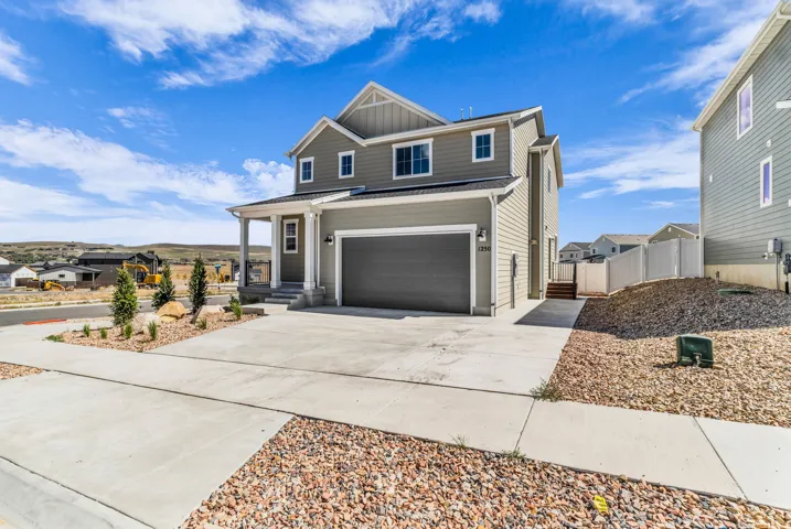 Contemporary two-story residence featuring a covered front porch, attached garage, and light gray siding