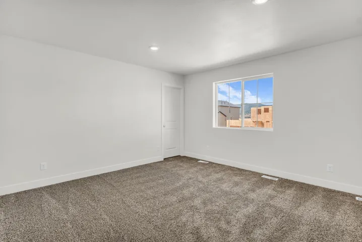 Neutral wall finishes with recessed lighting, a window with multiple panes, and grey carpeting
