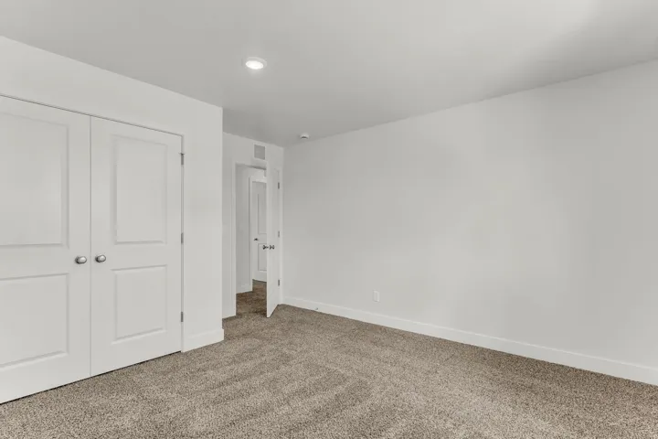 Recessed lighting, white walls, gray carpet, white trim, and a white paneled door