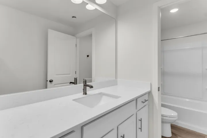 Double vanity with integrated sinks, brushed nickel fixtures, white cabinetry, and a full-width mirror