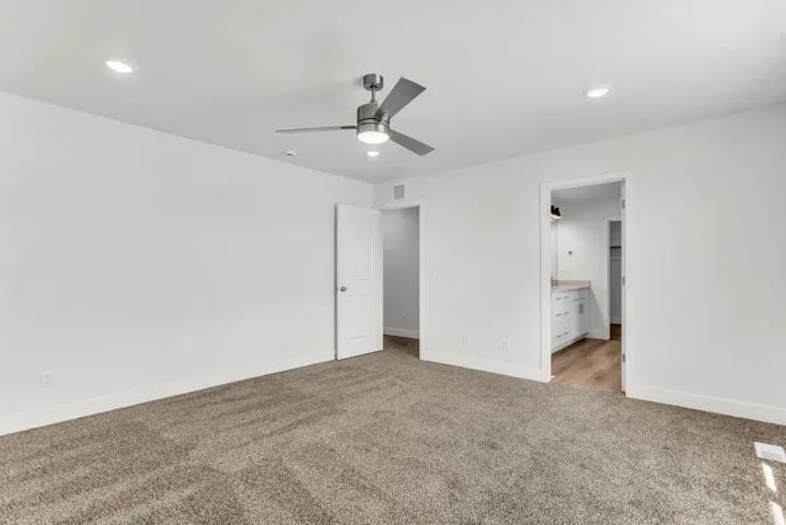 Recessed lighting, ceiling fan, white paneled doors, carpet flooring, and wood-finish flooring in the adjacent space