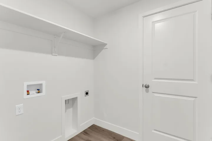 Utility area featuring a wall-mounted shelf, wood-finish flooring, and a panel door