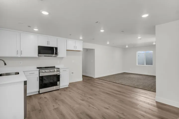 Kitchen featuring white cabinetry, stainless steel appliances, and wood-finish flooring