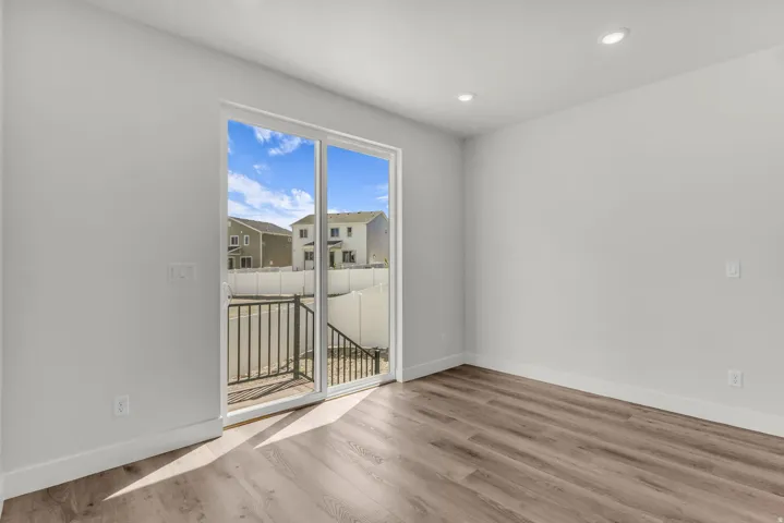 Sliding glass door to an outdoor landing, wood-finish flooring, recessed lighting, and crisp white walls
