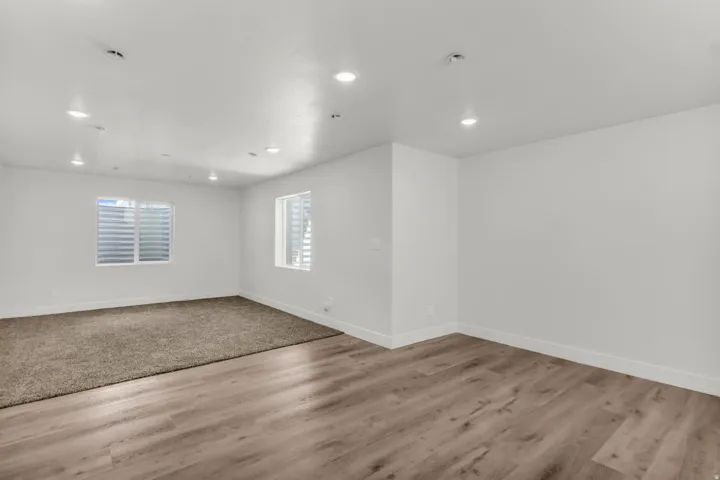 Recessed lighting, white walls, two windows, wood-finish flooring, and carpeted area