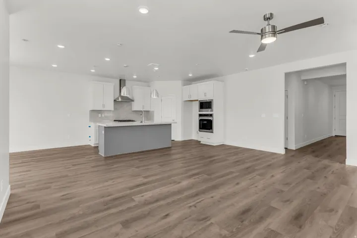 Open-concept living space with wood-finish flooring, recessed lighting, and a contemporary ceiling fan