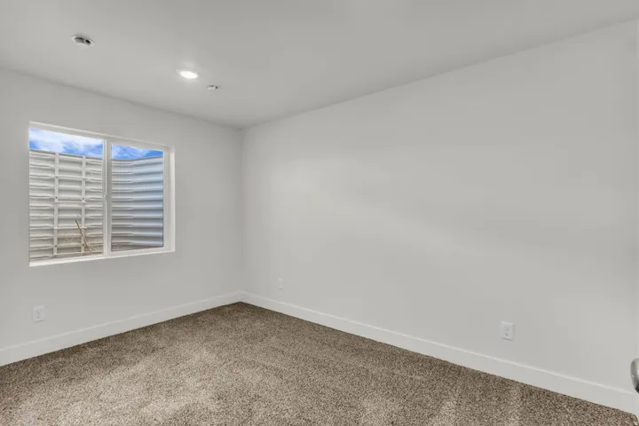 Recessed ceiling lighting, white walls, white trim, and carpet flooring