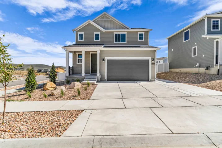 Two-story residence featuring a covered front porch with white columns, an attached two-car garage, and a concrete driveway