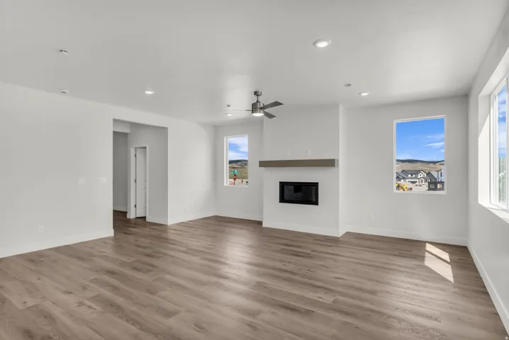 Spacious room featuring wood-finish flooring, a contemporary fireplace with a wood mantle, and multiple windows