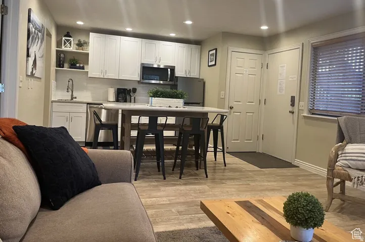 Kitchen featuring white shaker cabinetry, stainless steel appliances, and a central island with countertop seating