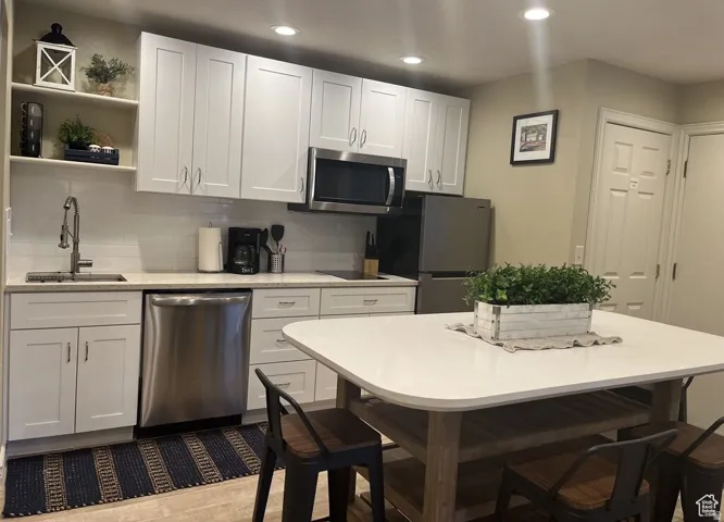 White shaker-style cabinetry, stainless steel appliances, light-toned countertops, and recessed lighting