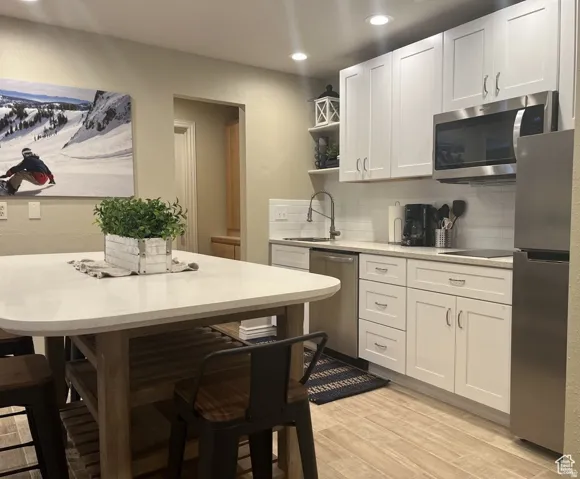 Kitchen featuring white shaker-style cabinetry, stainless steel appliances, a subway tile backsplash, and light-toned countertops