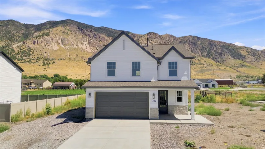 Two-story residence featuring white siding, a dark gray roof, and a stone facade accent