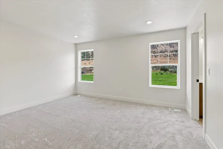 Recessed lighting, light gray carpeting, white walls, and two multi-pane windows