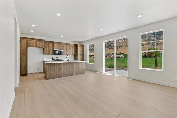 Open-concept kitchen featuring wood-finish cabinetry, a large kitchen island with a light-toned countertop, and stainless steel appliances