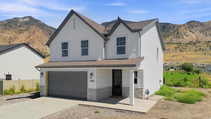 Two-story residence featuring white siding, a dark gray garage door, and a covered entry