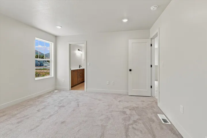 Neutral-toned carpeting, recessed ceiling lighting, and crisp white walls
