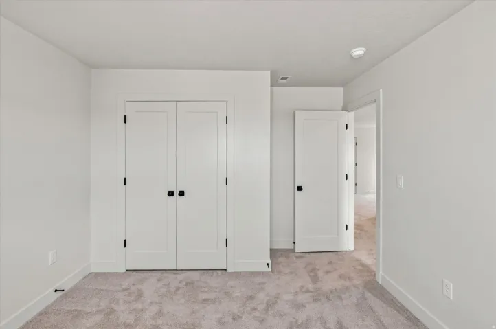 Plush carpet flooring, white walls, white doors with matte black hardware, and crisp white trim