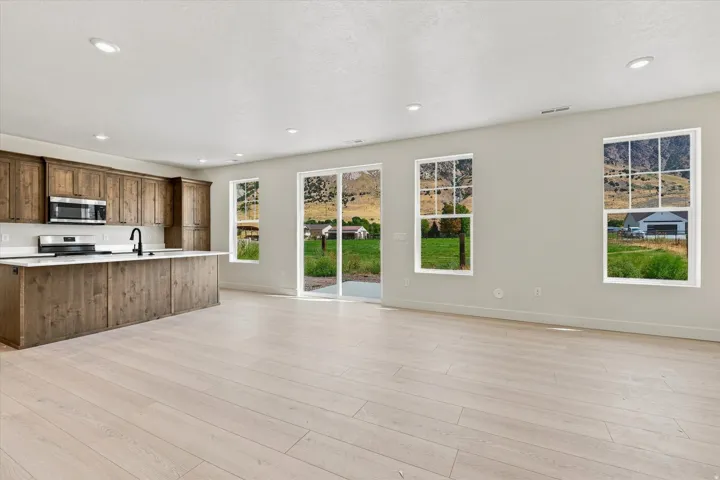 Spacious open-concept area featuring light wood-finish flooring and recessed lighting