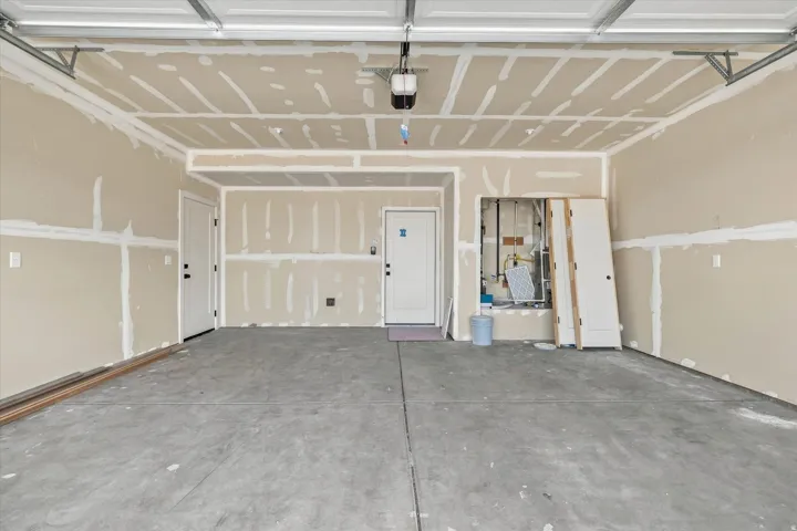 Spacious garage with concrete flooring, two entry doors, and overhead garage door track system