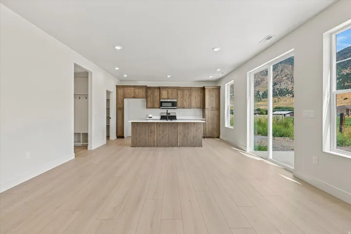 Open-concept living space with light wood-finish flooring, recessed lighting, and large sliding glass doors