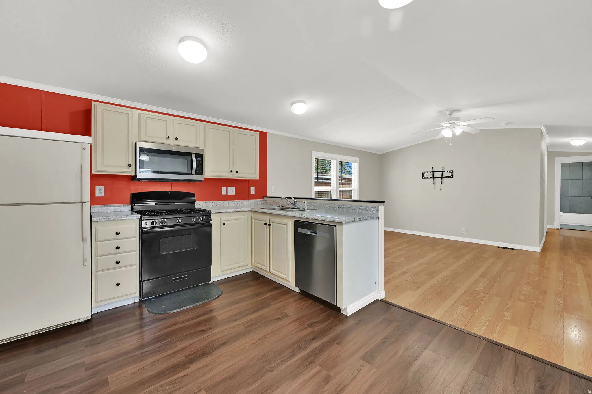Kitchen featuring wood-finish flooring, cream cabinetry, a built-in microwave, and a gas range