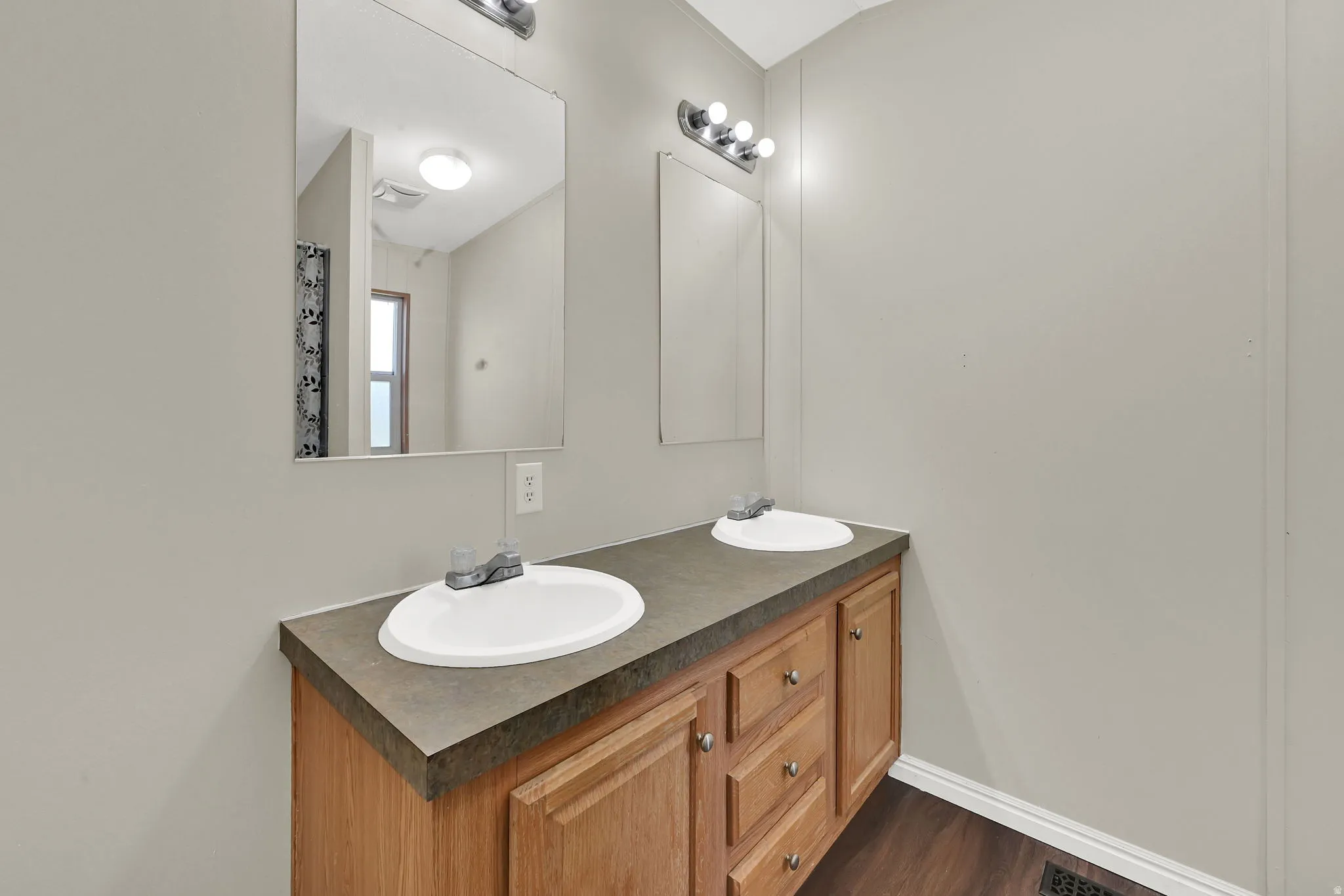 Dual vanity with integral sinks, oak-finish cabinetry, and dark countertop