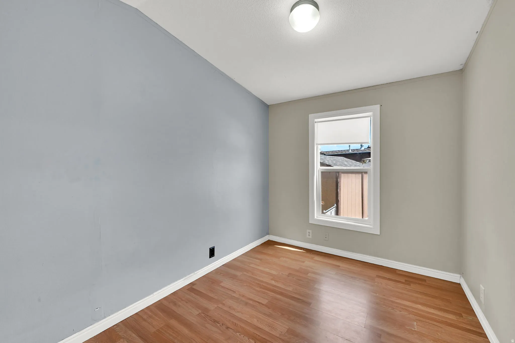 Wood-finish flooring, single window with white trim, and ceiling-mounted light fixture