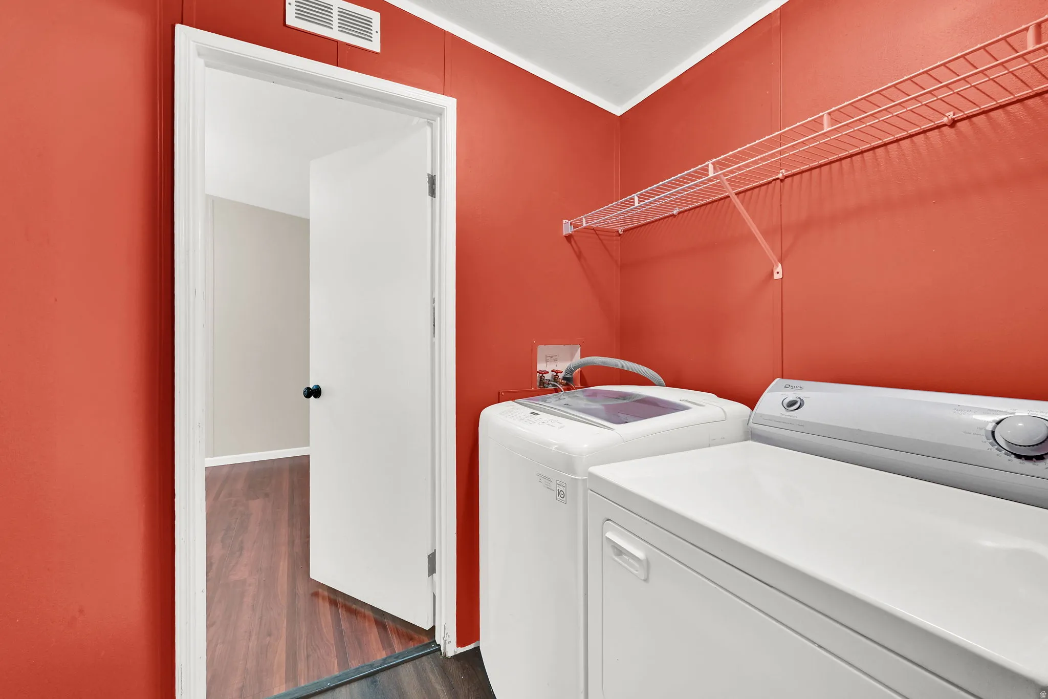 Laundry area with wire shelving and wood-finish flooring