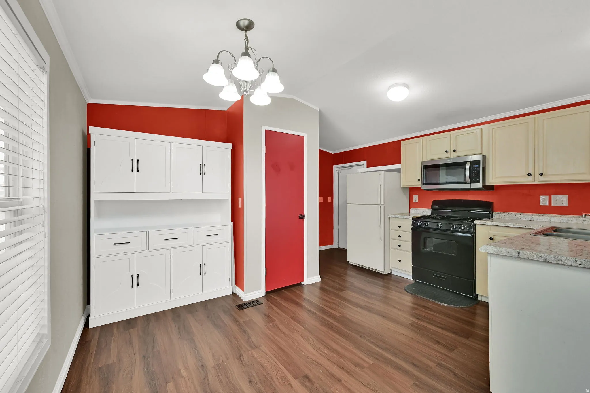 Wood-finish flooring with white built-in cabinetry, an overhead light fixture, and light-toned upper and lower cabinets