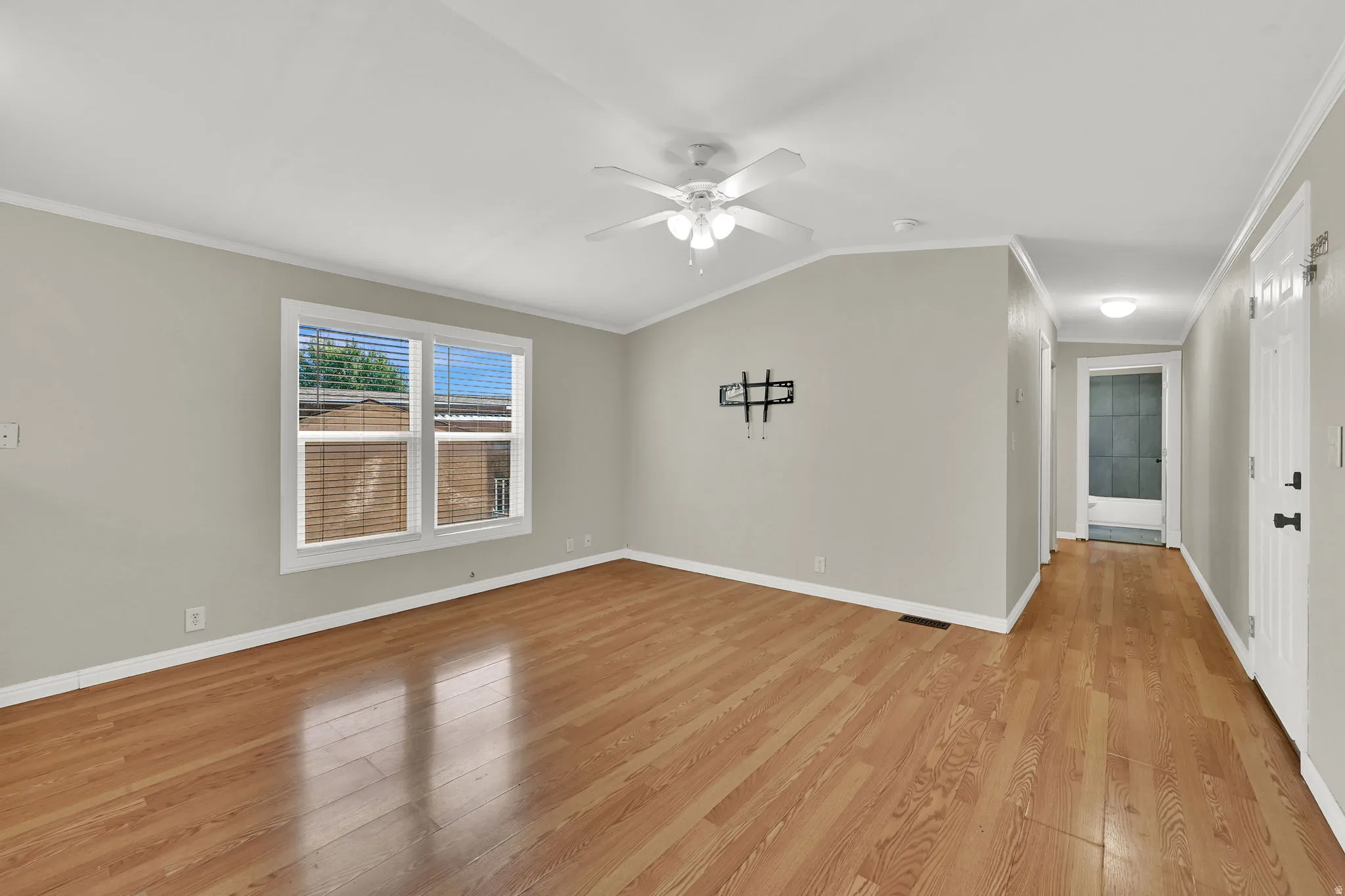 Wood-finish flooring, white trim, and a ceiling fan with light fixture
