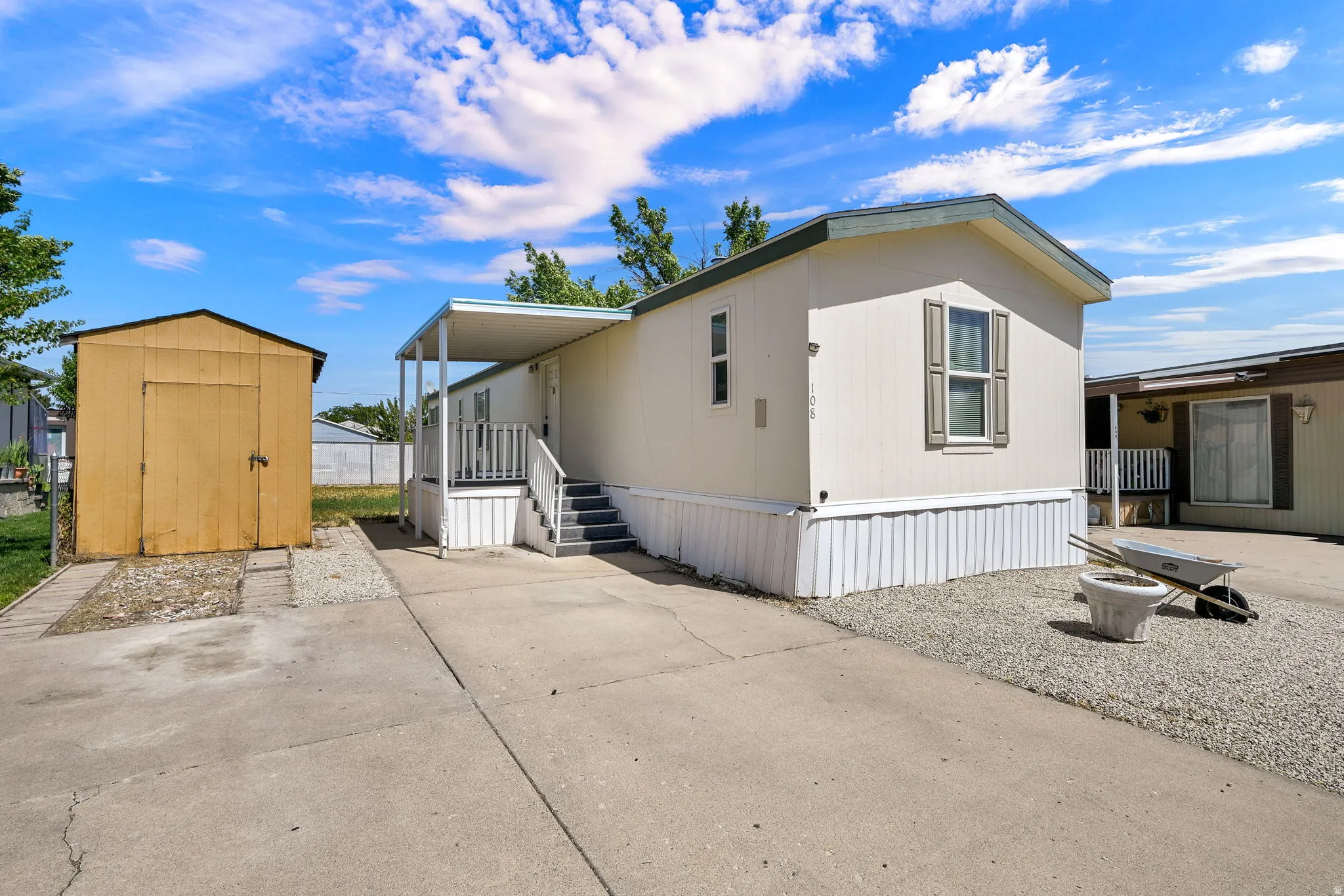 Exterior featuring a covered porch, privacy shutters, and a detached storage shed