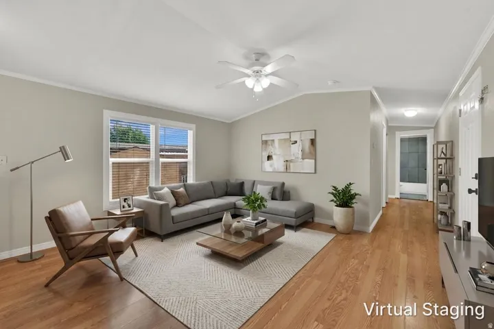 Wood-finish flooring throughout, vaulted ceiling with a ceiling fan, and large windows with blinds