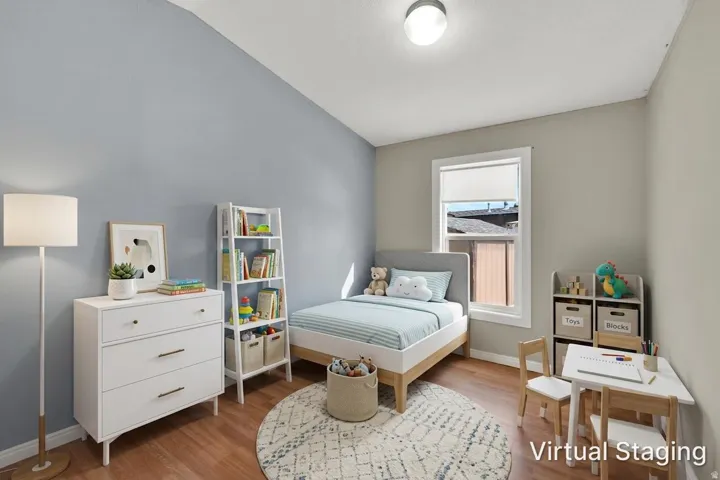 Wood-finish flooring, a window with roller shade, and a flush mount ceiling light