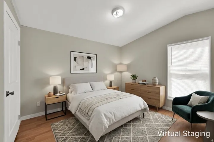 Wood-finish flooring, white paneled door with dark hardware, vaulted ceiling, recessed lighting, and a window with blinds